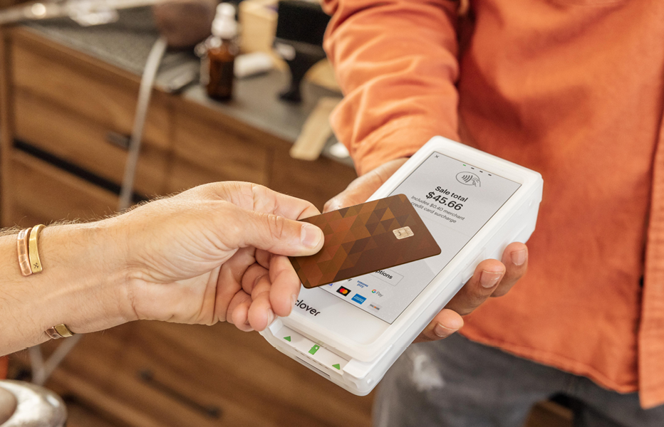 Customer making contactless payment with credit card on Clover terminal showing $45.66 sale.