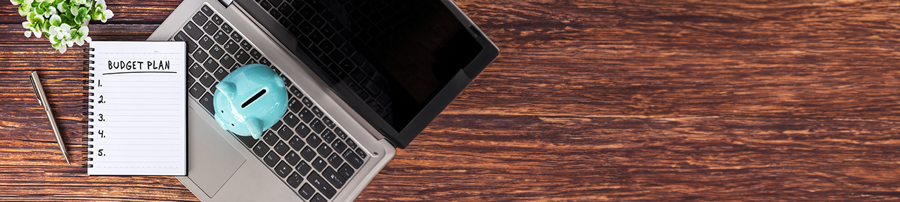 Laptop, piggy bank and notepad on desk