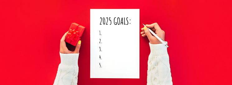 Person holding pen and red present jotting down 2025 goals