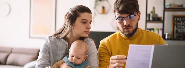 Man and woman with baby reviewing bank statements 