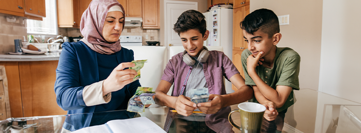 Mother and two sons counting dollar bills from piggy bank