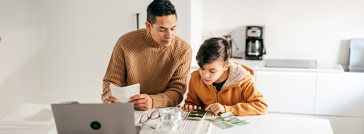 Dad helping son with math homework with calculator