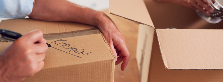 Person labelling moving box "kitchen" with sharpie