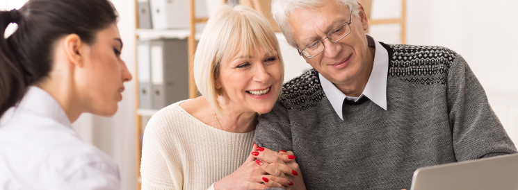 Retired couple looking at finances on laptop with advisor