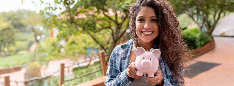 Smiling woman holding a pink ceramic piggy bank