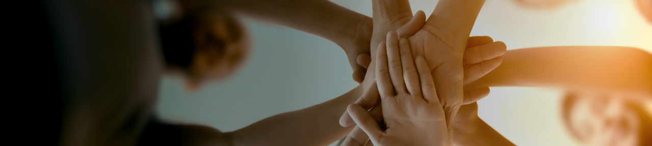 Group of people putting hands together in the middle of a circle