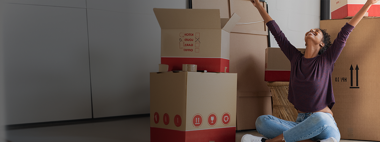 Woman sitting and celebrating move amogst moving boxes