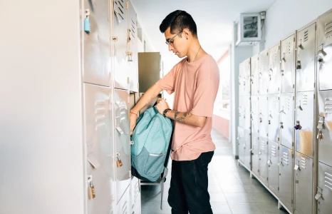 Student unpacking backpack into locker